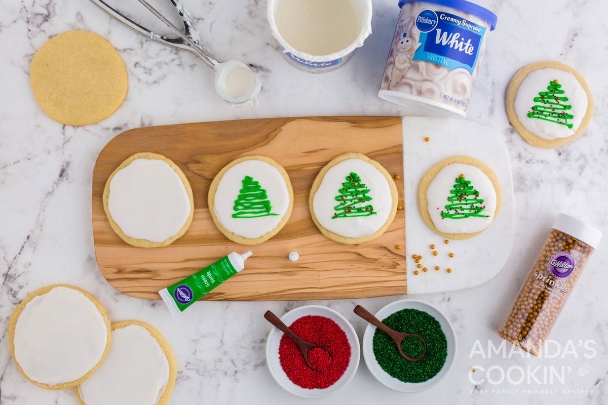 adding christmas trees with decorator gel on iced cookies