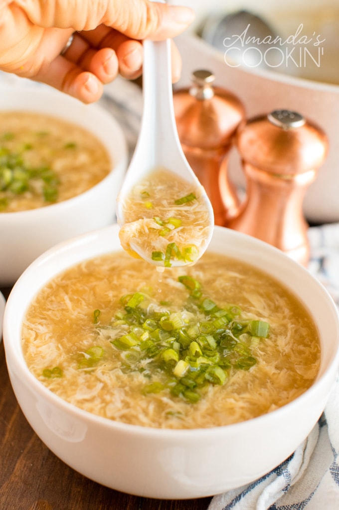 hand holding spoon of egg drop soup