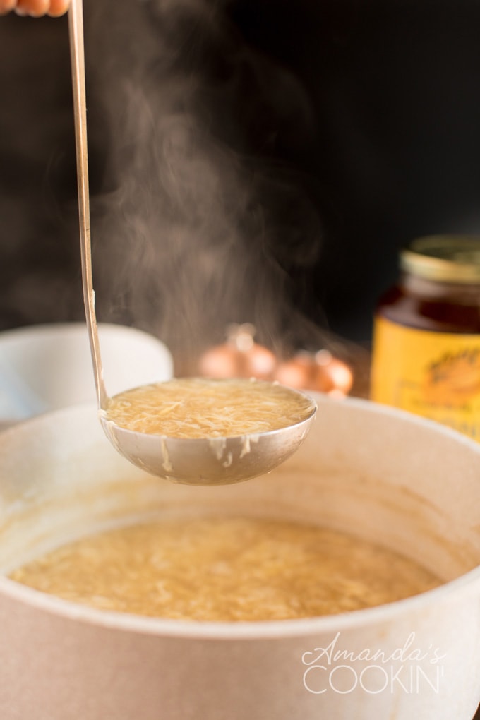ladle full of egg drop soup coming out of saucepan