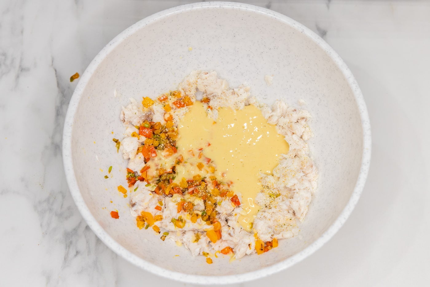 adding horseradish and sauces to fish mixture in a bowl
