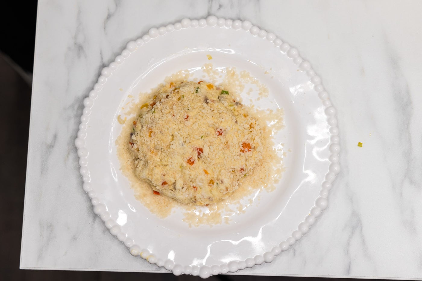 fish patty on top of breadcrumbs on a plate