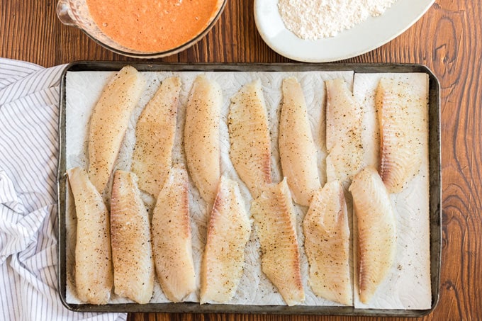 fish strips on paper towels seasoned with salt and pepper