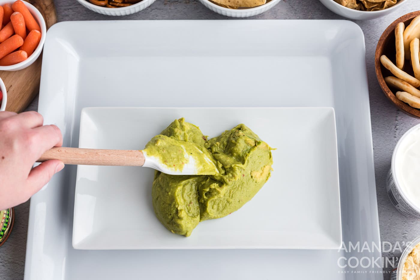 spreading guacamole on small platter