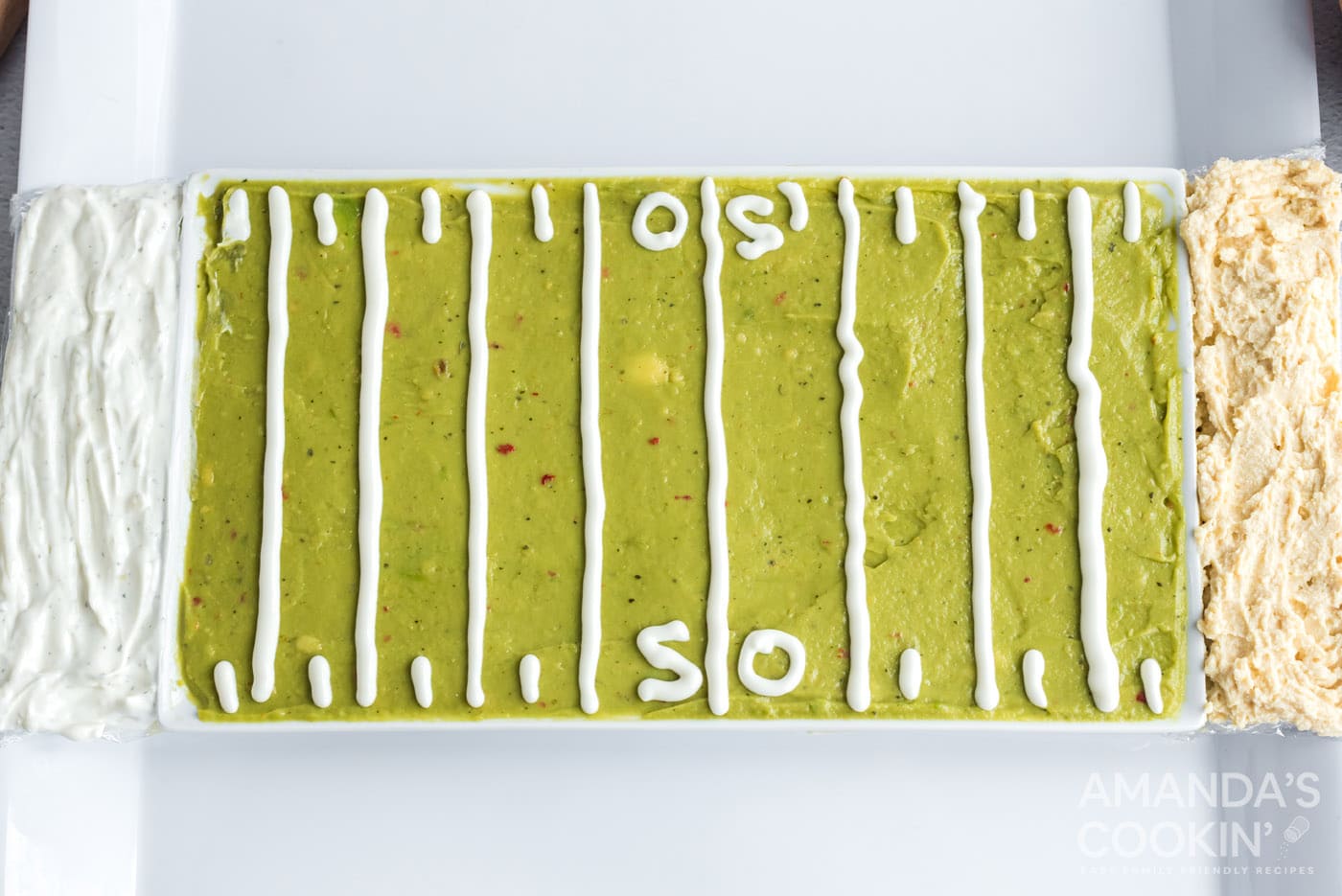 guacamole, french onion dip, and hummus on a tray with sour cream outline of football field