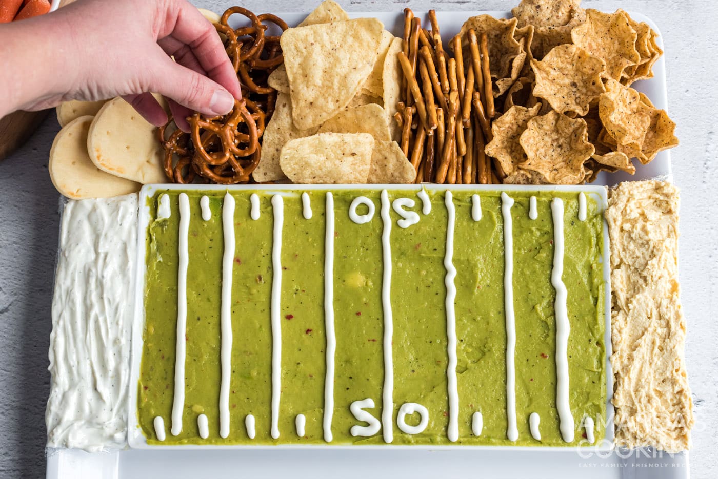 hand grabbing a pretzel on football party tray