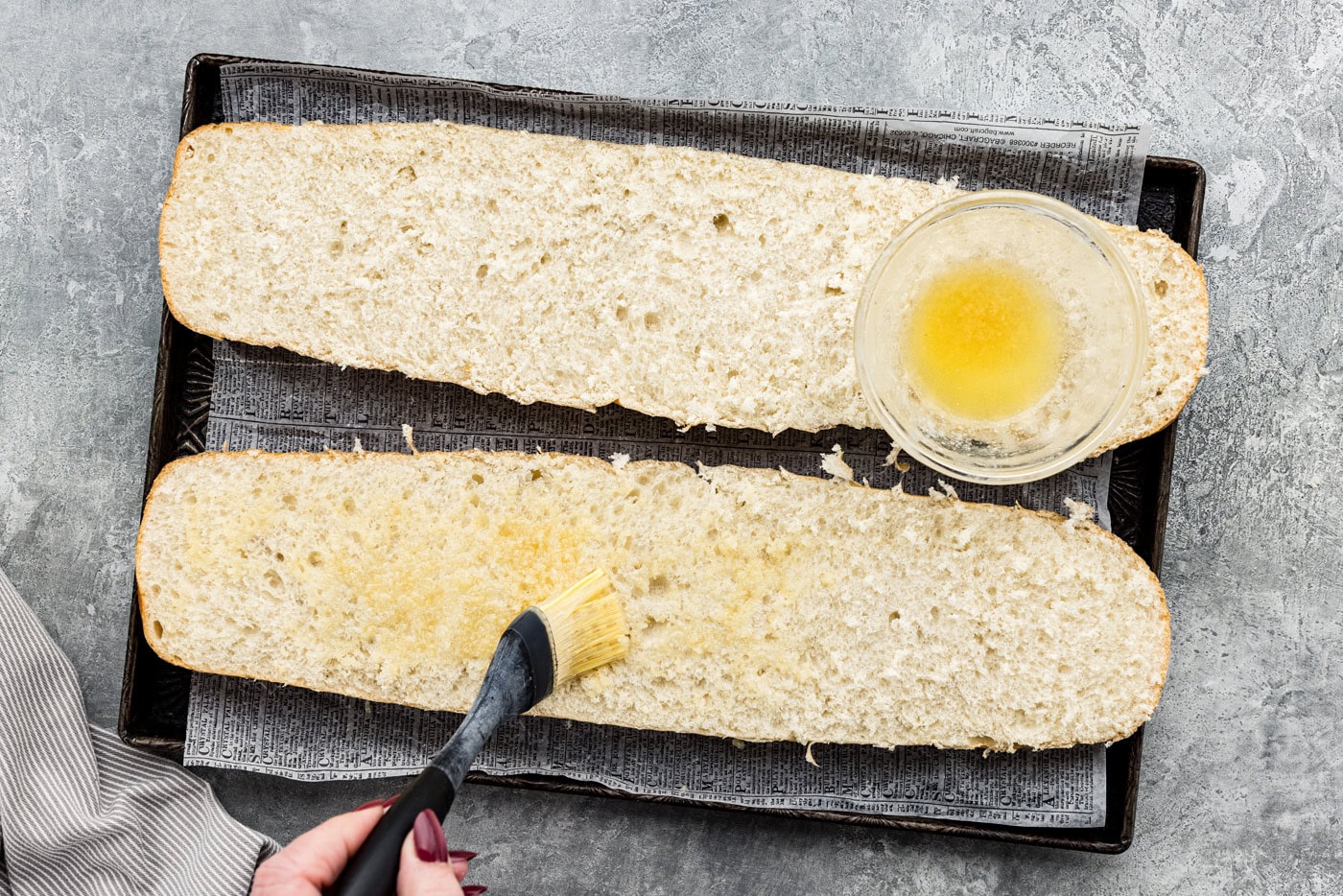 Basting garlic butter on halves of French bread