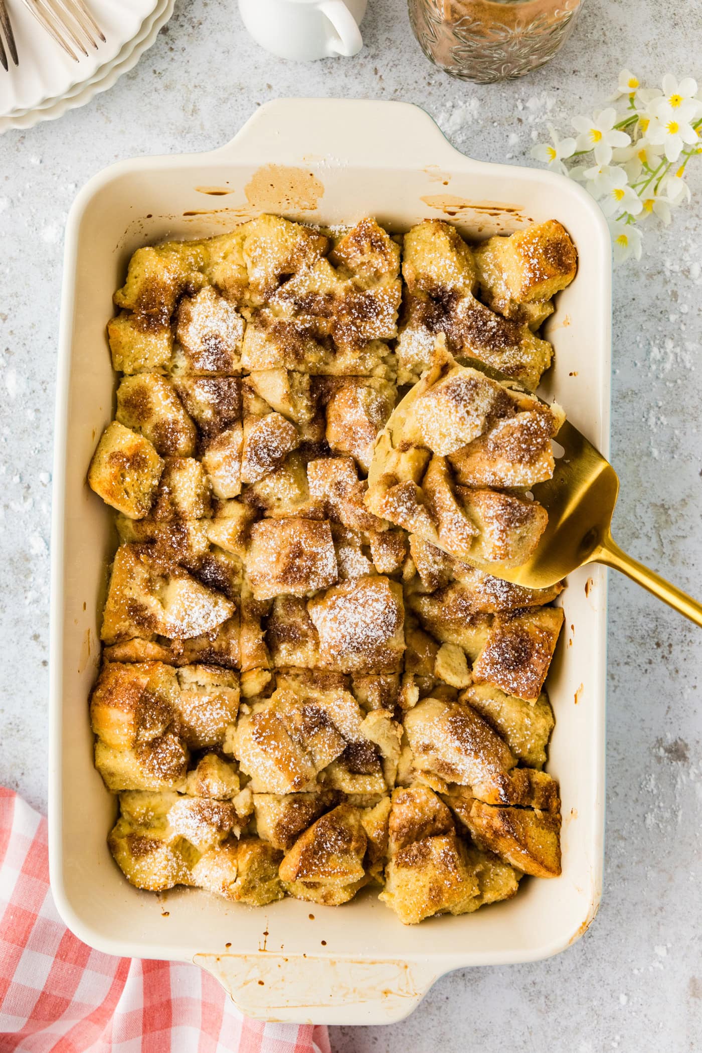 Spatula holding up a slice of French Toast Casserole above the baking dish of French Toast Casserole