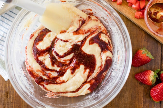 rubber spatula swirling jam into bowl of muffin batter