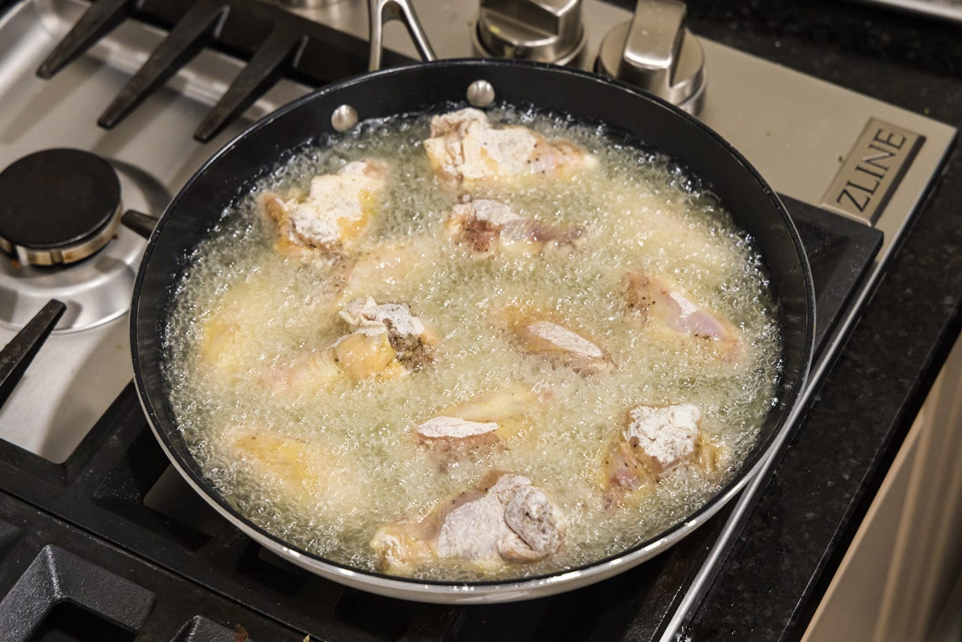 frying chicken wings in a skillet