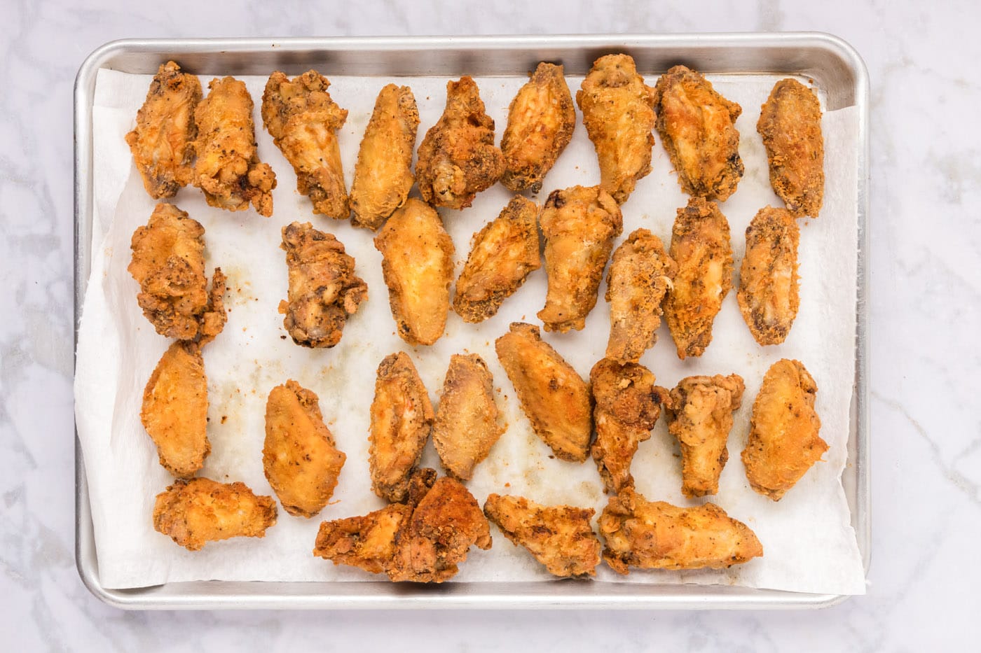fried chicken wings on a baking sheet lined with paper towels
