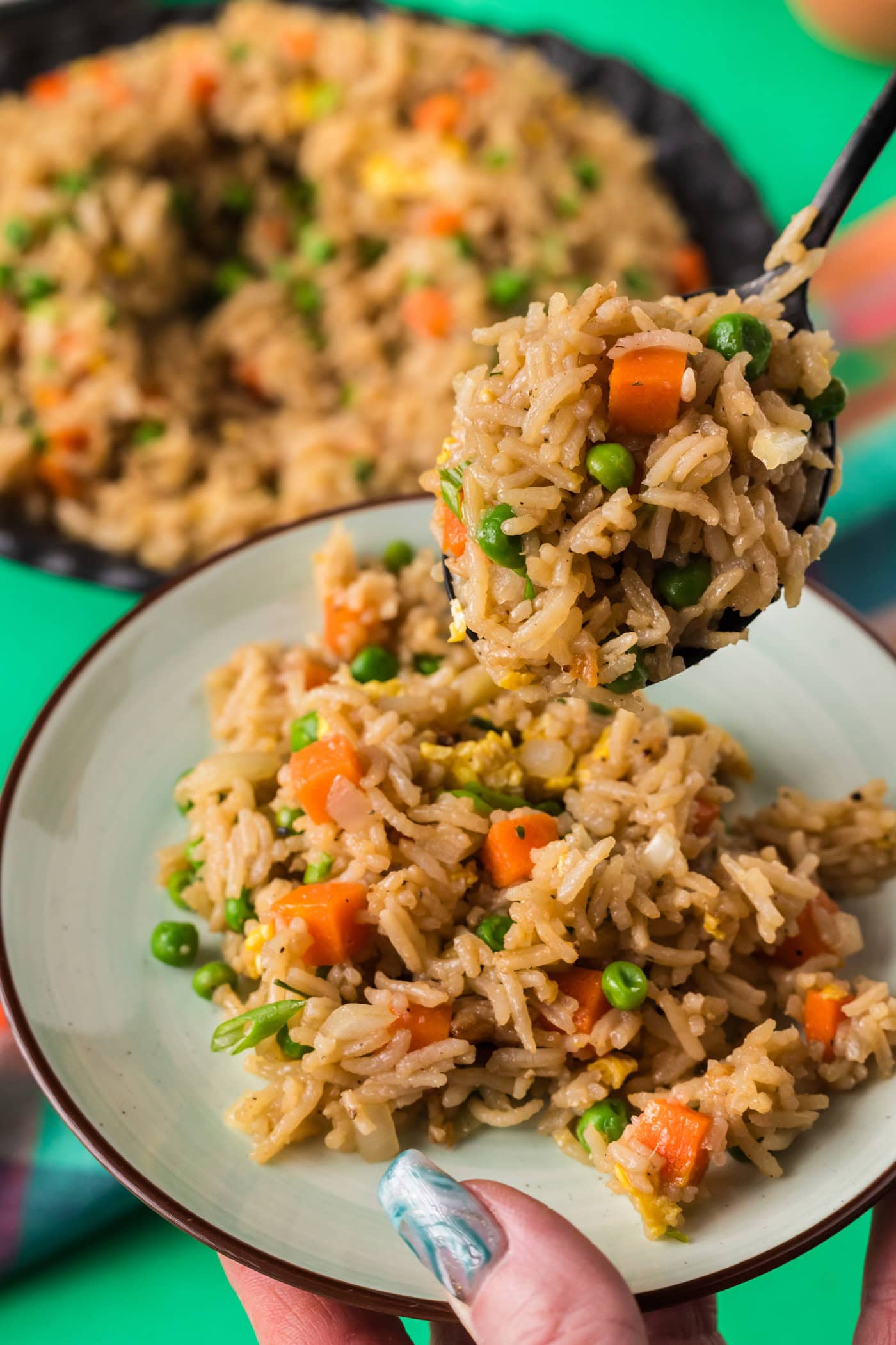 Spoonful of Vegetable Fried Rice being served onto a plate
