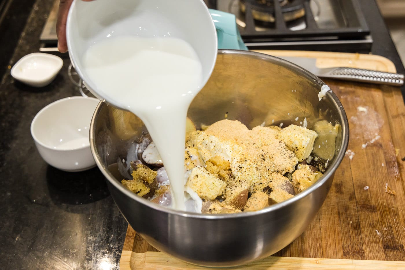 pouring heavy whipping cream into bowl of sour cream, butter, potatoes, and garlic