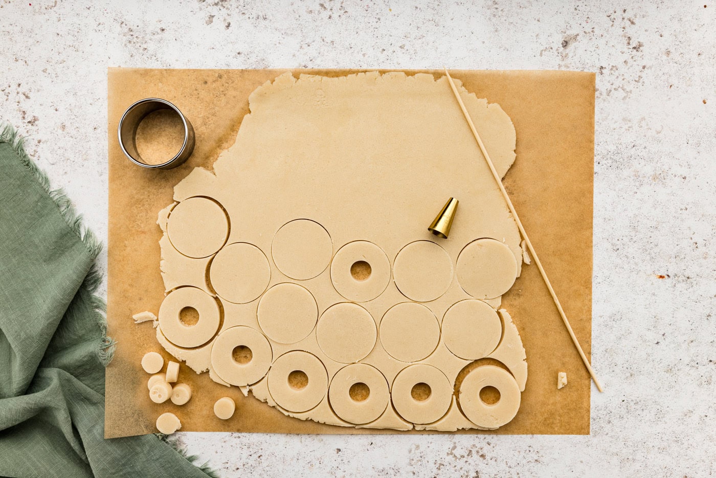 Small end of a piping tip piercing a hole through cookie dough circles