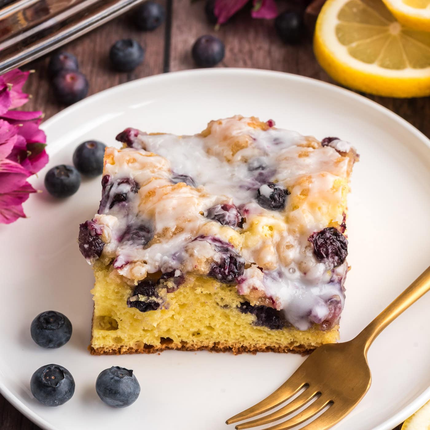 Close up photo of a slice of Glazed Lemon Blueberry Cake on a plate