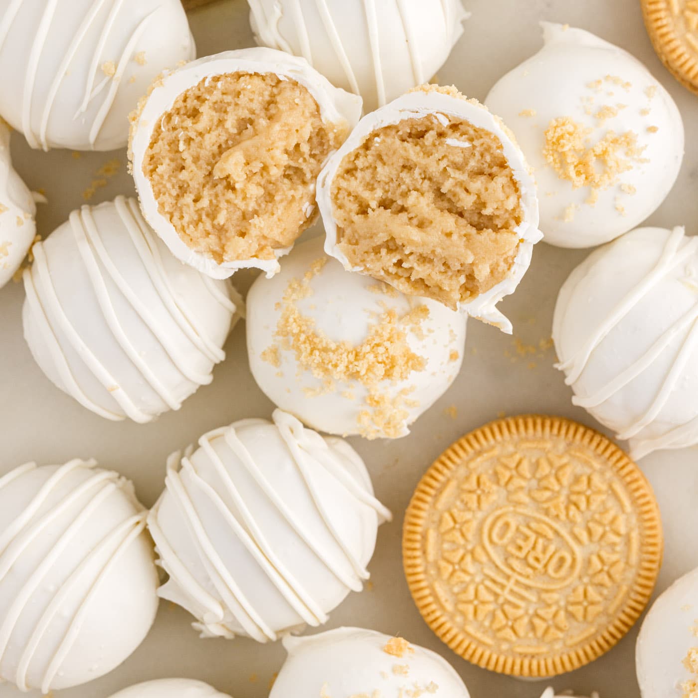 Close up photo of a Golden Oreo Truffle cut in half resting on top of more Golden Oreo Truffles