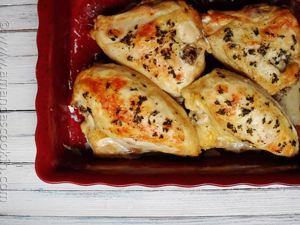 An overhead photo of golden roasted chicken breasts in a red roasting pan.