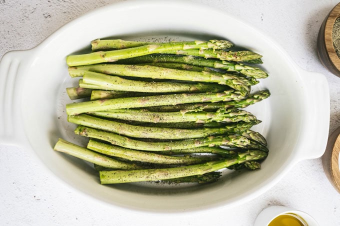 asparagus in a dish with salt and pepper in dishes around it