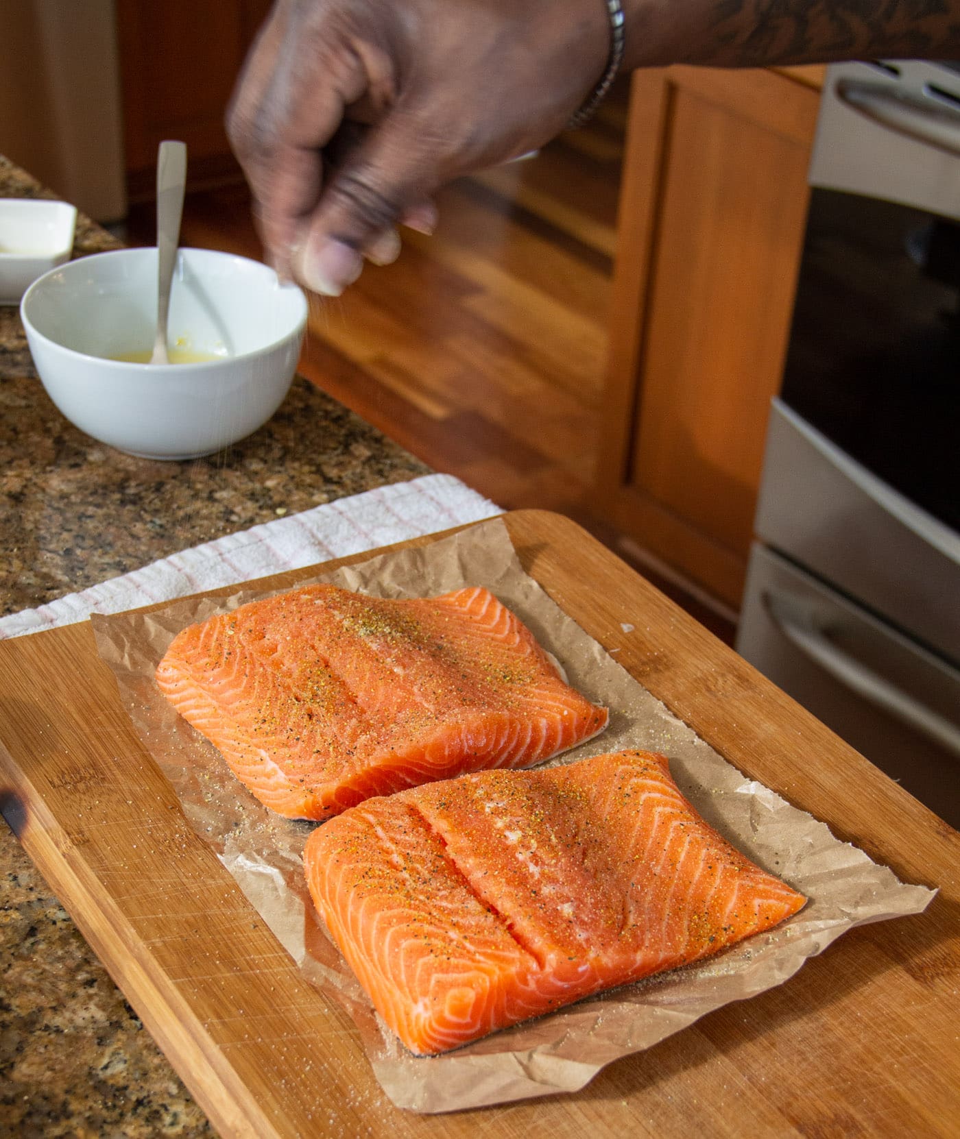 sprinkling lemon pepper and garlic salt on salmon