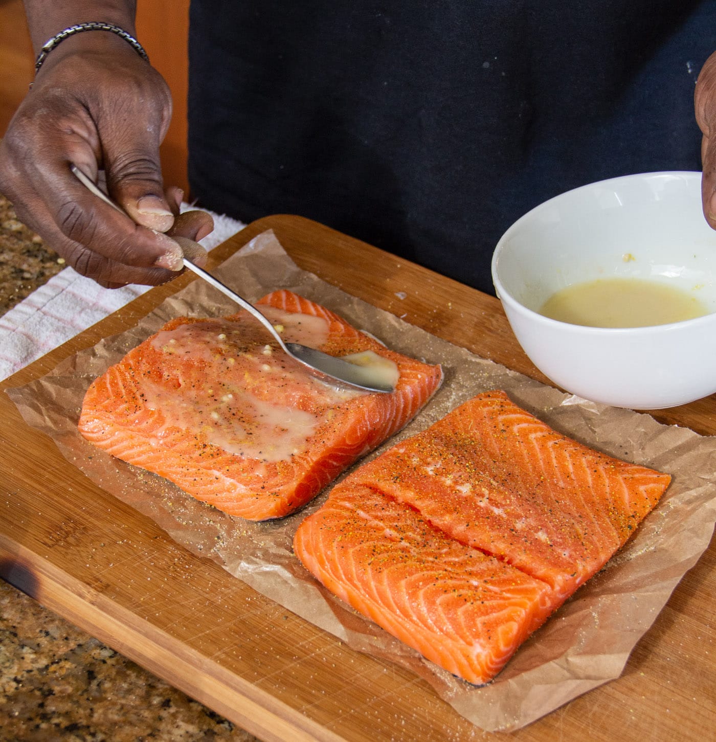 spooning lemon marinade over salmon