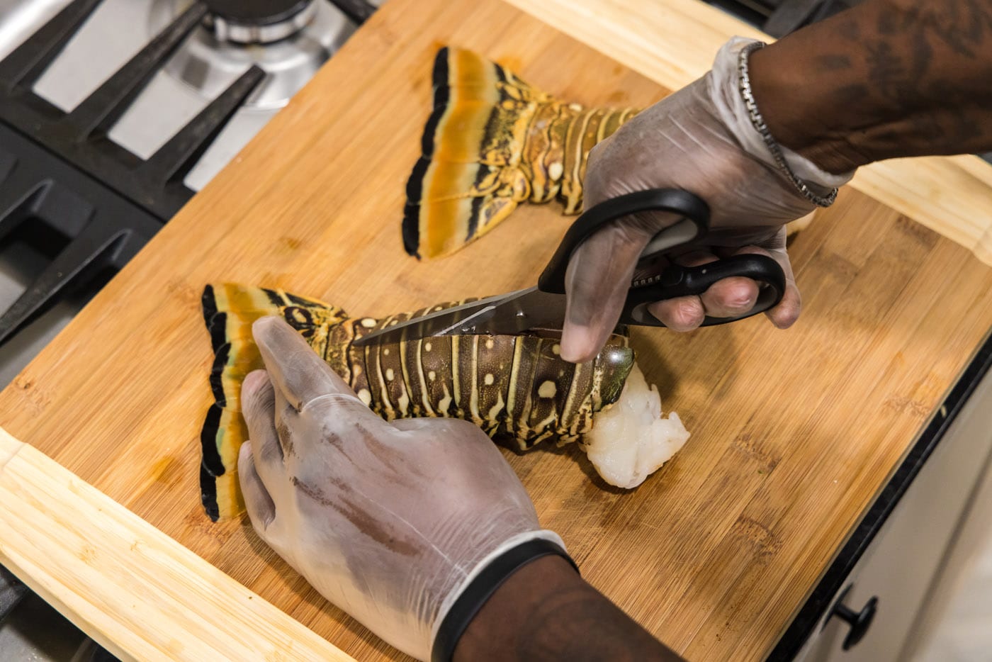 using kitchen shears to cut down the center of lobster tails
