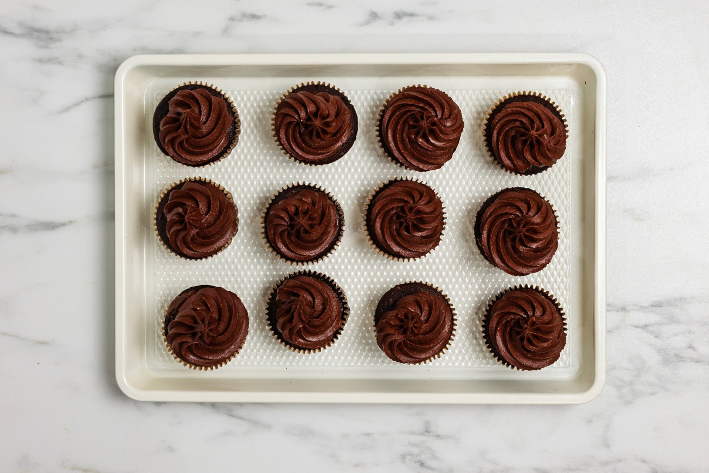 Chocolate frosted cupcakes on a baking sheet