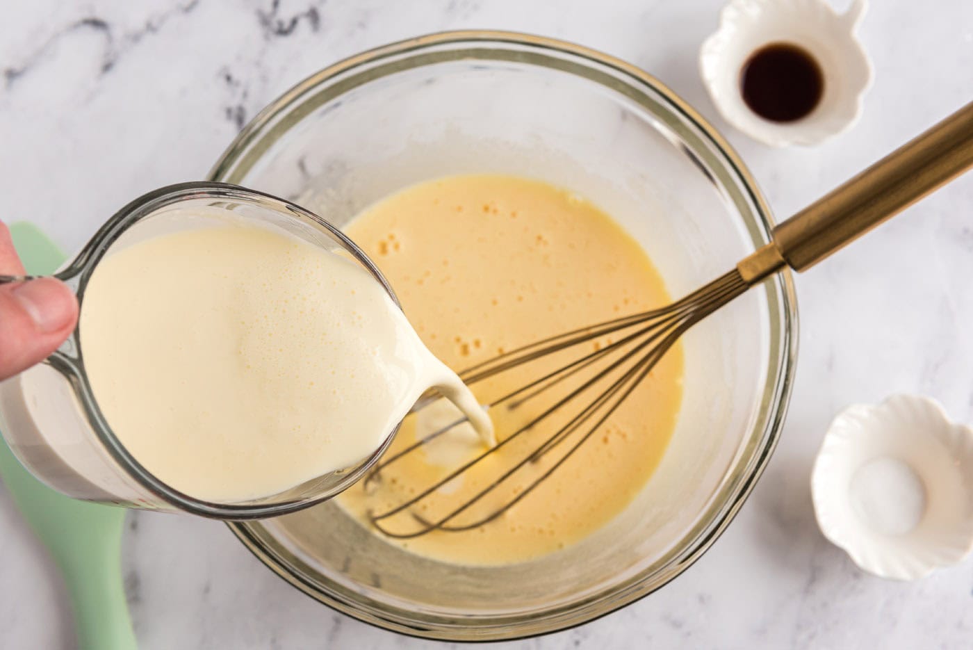 pouring heavy cream into bowl of whisked eggs and sugar mixture