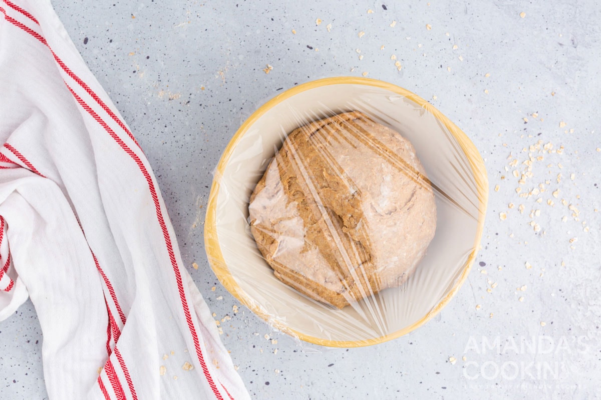 bowl of bread dough covered in plastic wrap
