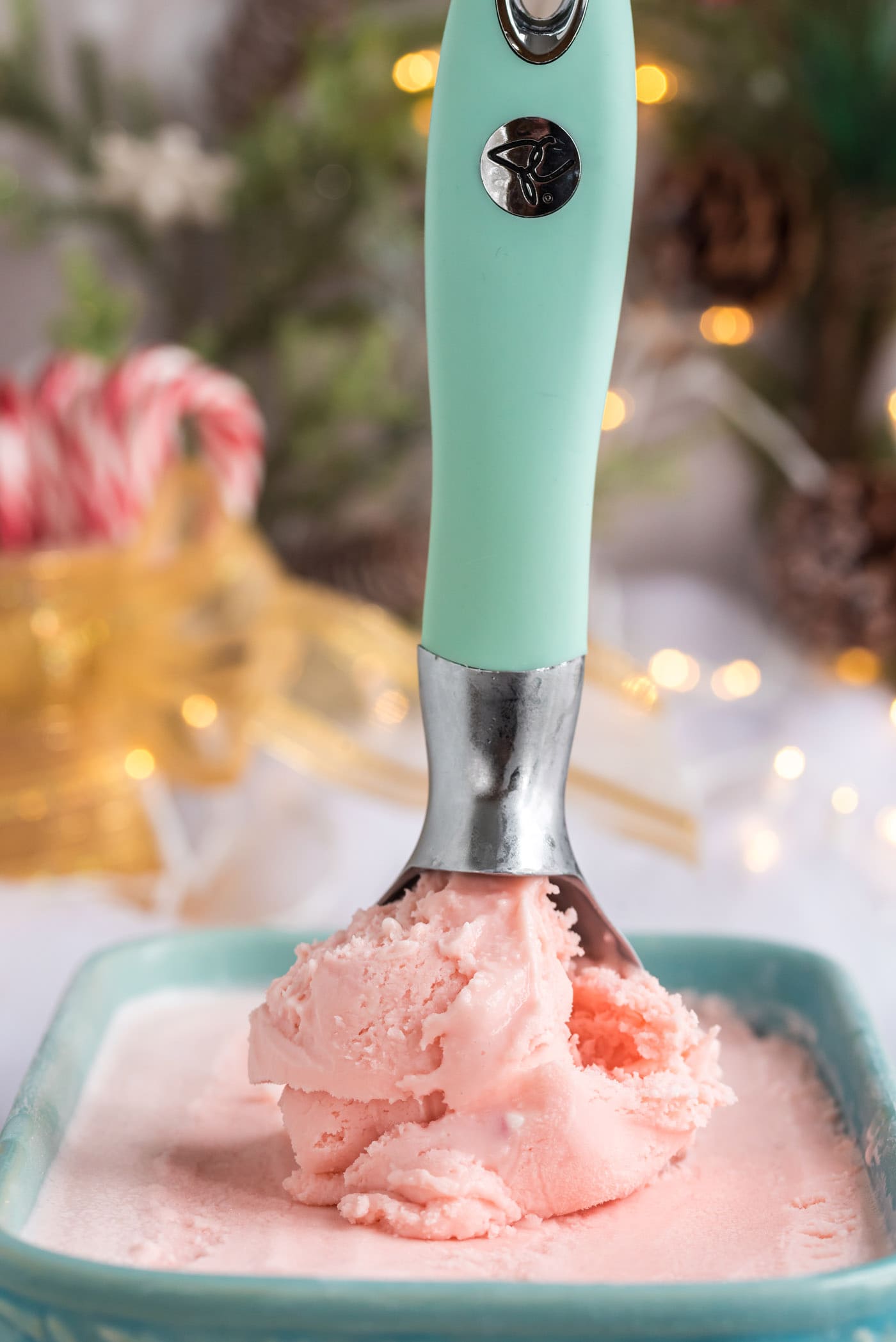 Scoop of Homemade Peppermint Ice Cream in an ice cream scoop resting in a container of Homemade Peppermint Ice Cream