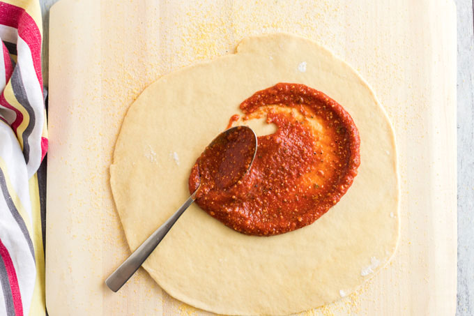 adding sauce to pizza dough