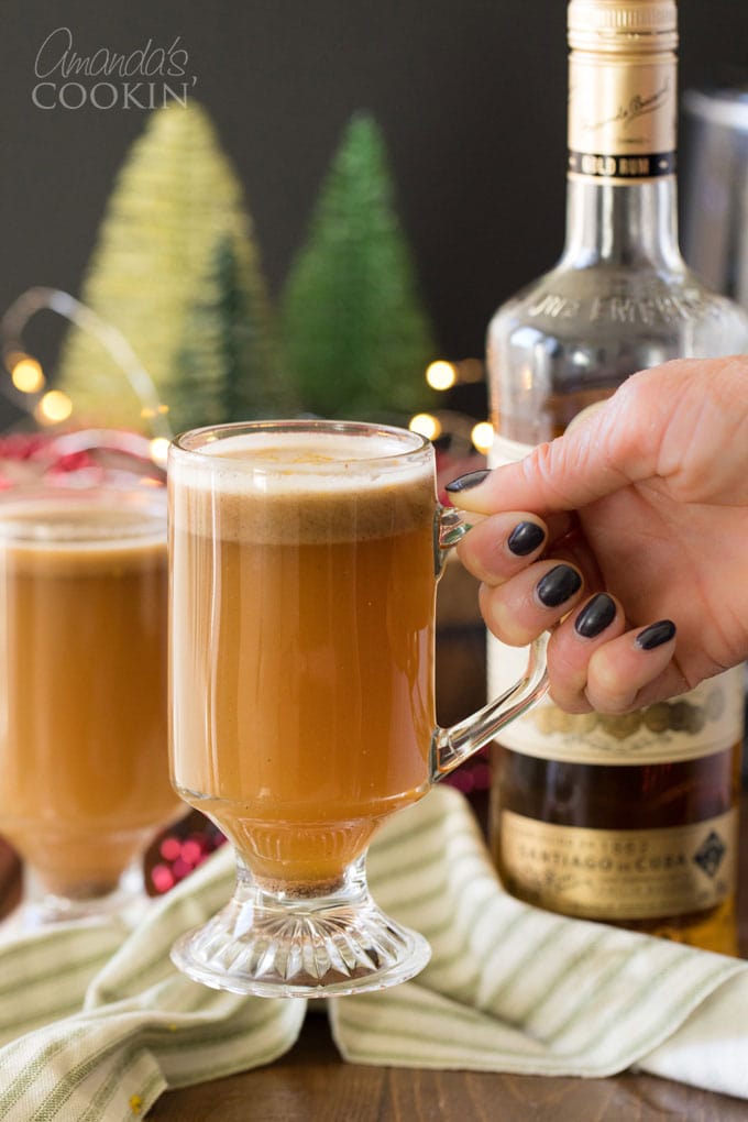woman's hand picking up glass of hot buttered rum