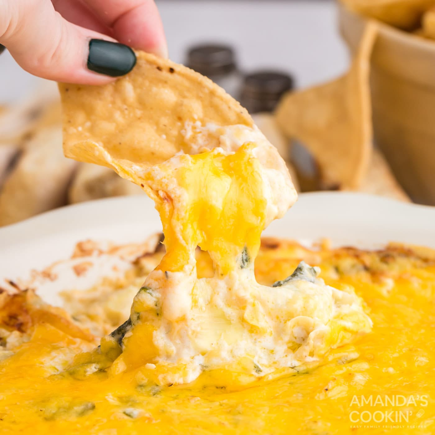 chip pulling spinach dip from bowl