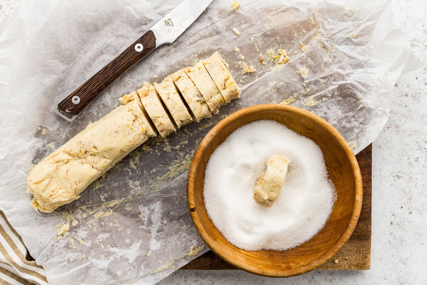 sliced cookie dough in a bowl of sugar