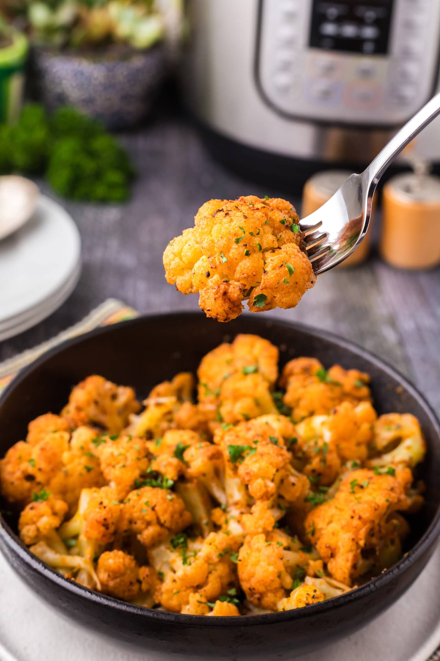 Piece of Instant Pot Cauliflower on a fork held above a bowl of Instant Pot Cauliflower