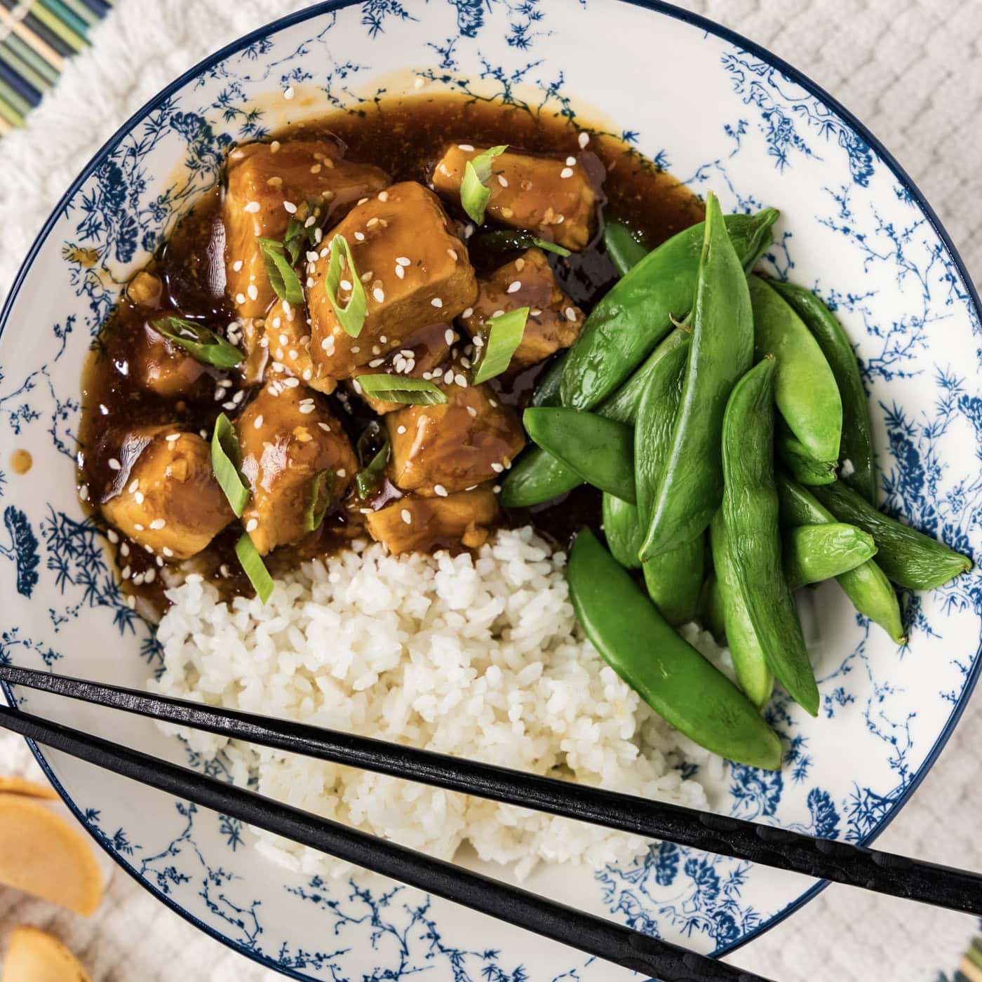 Close up photo of a bowl of Instant Pot Honey Garlic Chicken with rice and sugar snap peas
