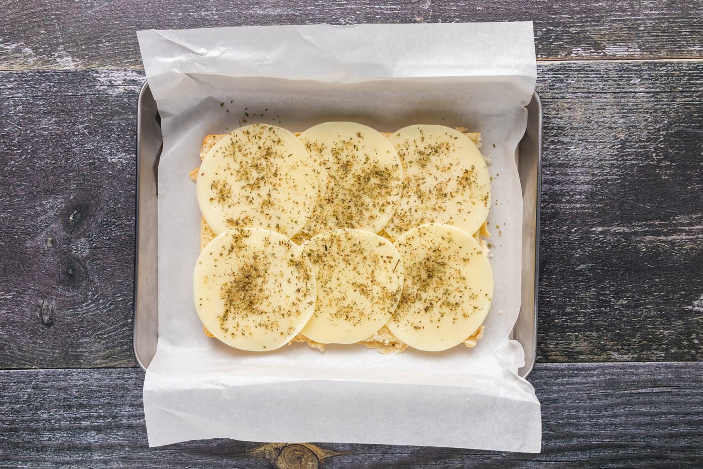 provolone cheese with italian seasoning on top of slider buns