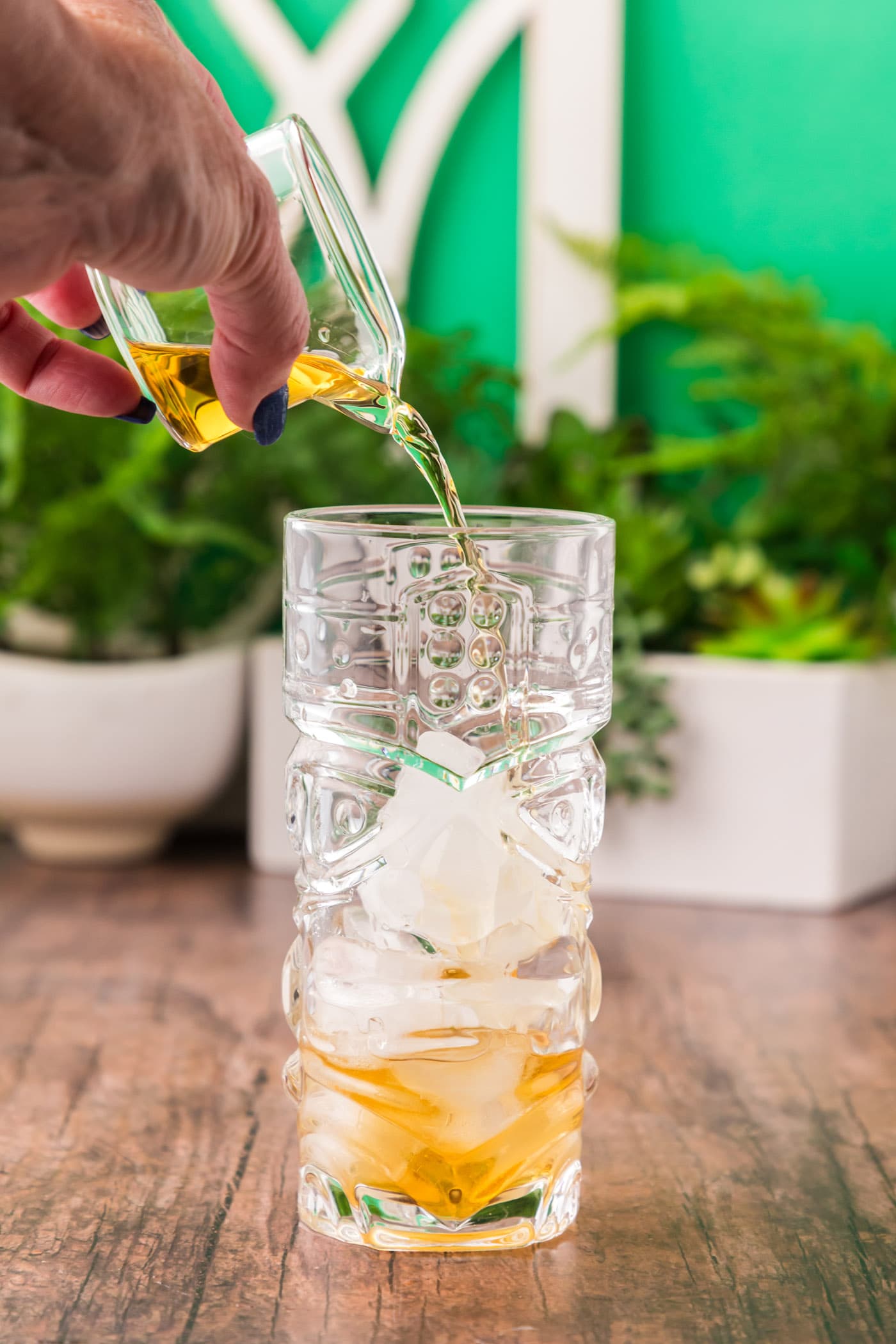 pouring rum into glass with ice