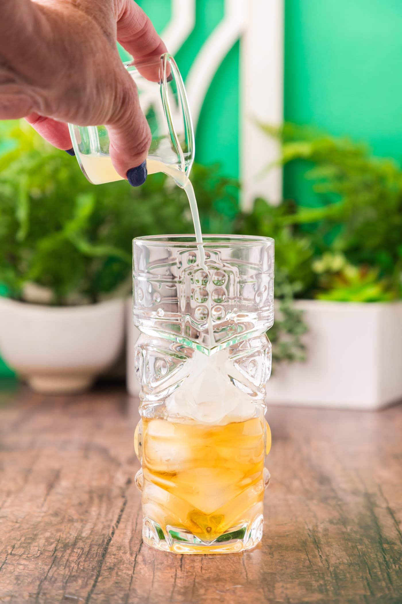 adding lime juice to glass of rum