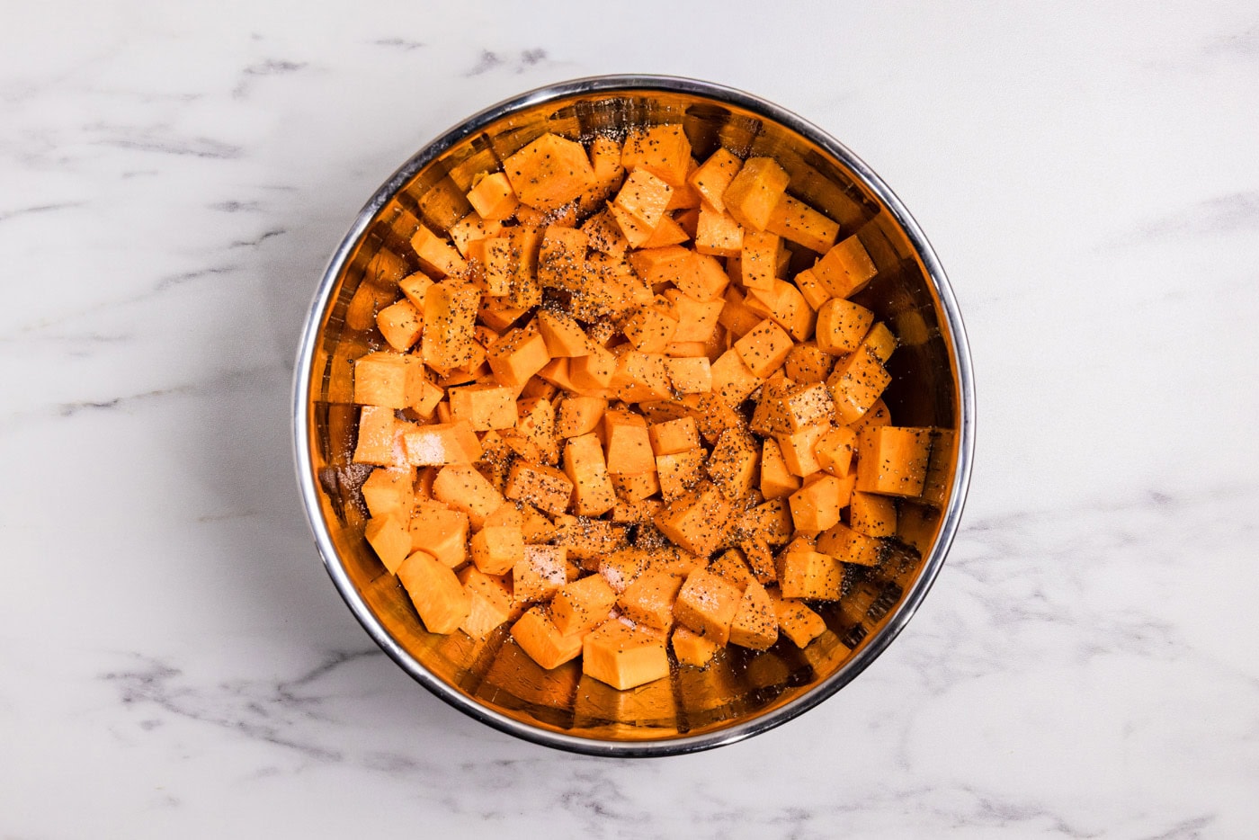cubed sweet potatoes in a bowl with salt and pepper