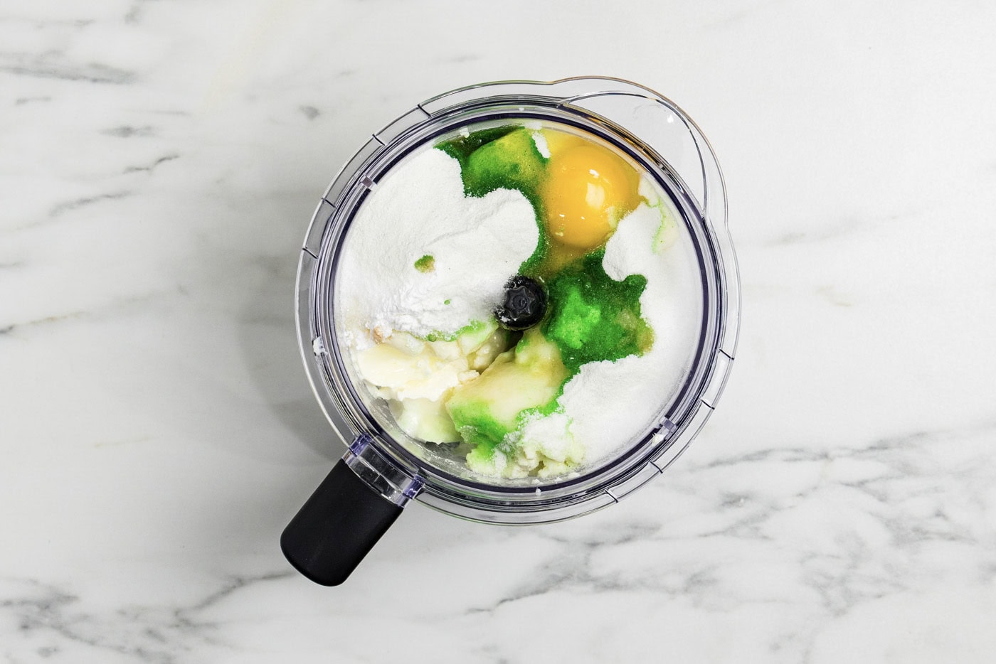 overhead photo of keto lime cheesecake ingredients in a food processor bowl