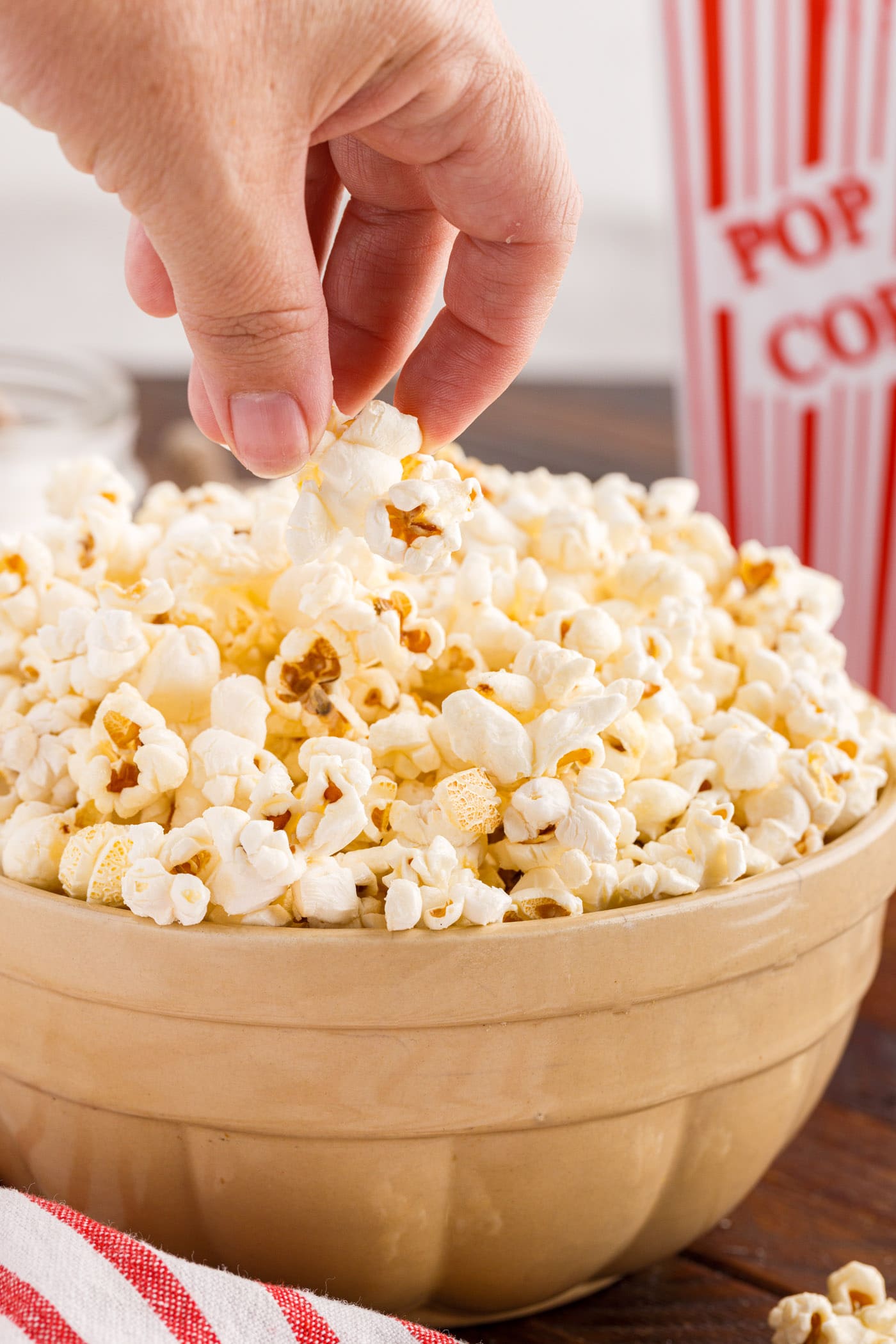Hand grabbing Kettle Corn out of a bowl of Kettle Corn