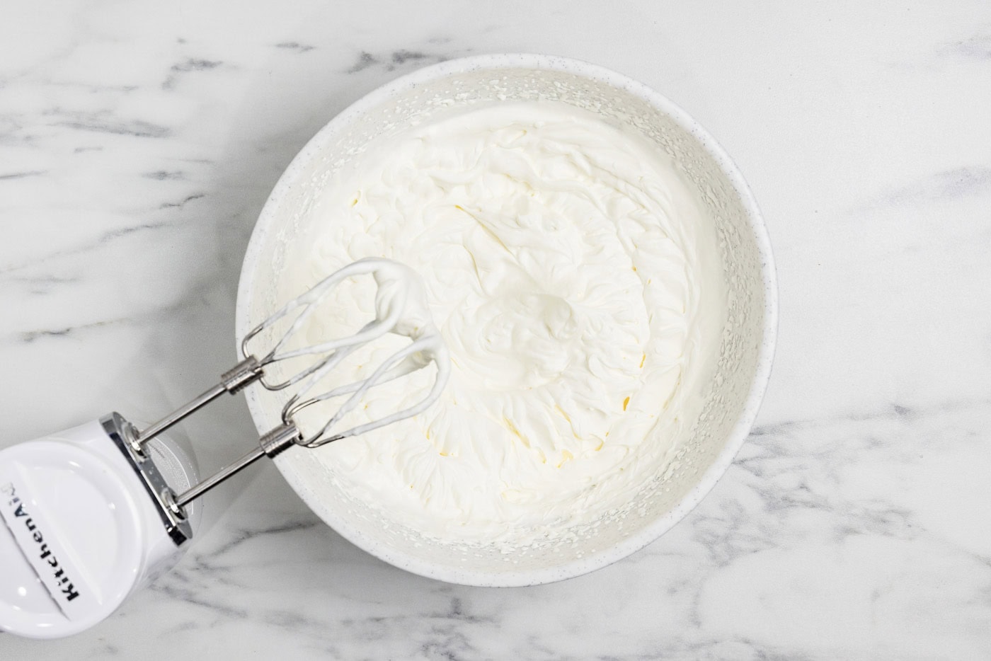 whipped cream in a bowl with electric mixer