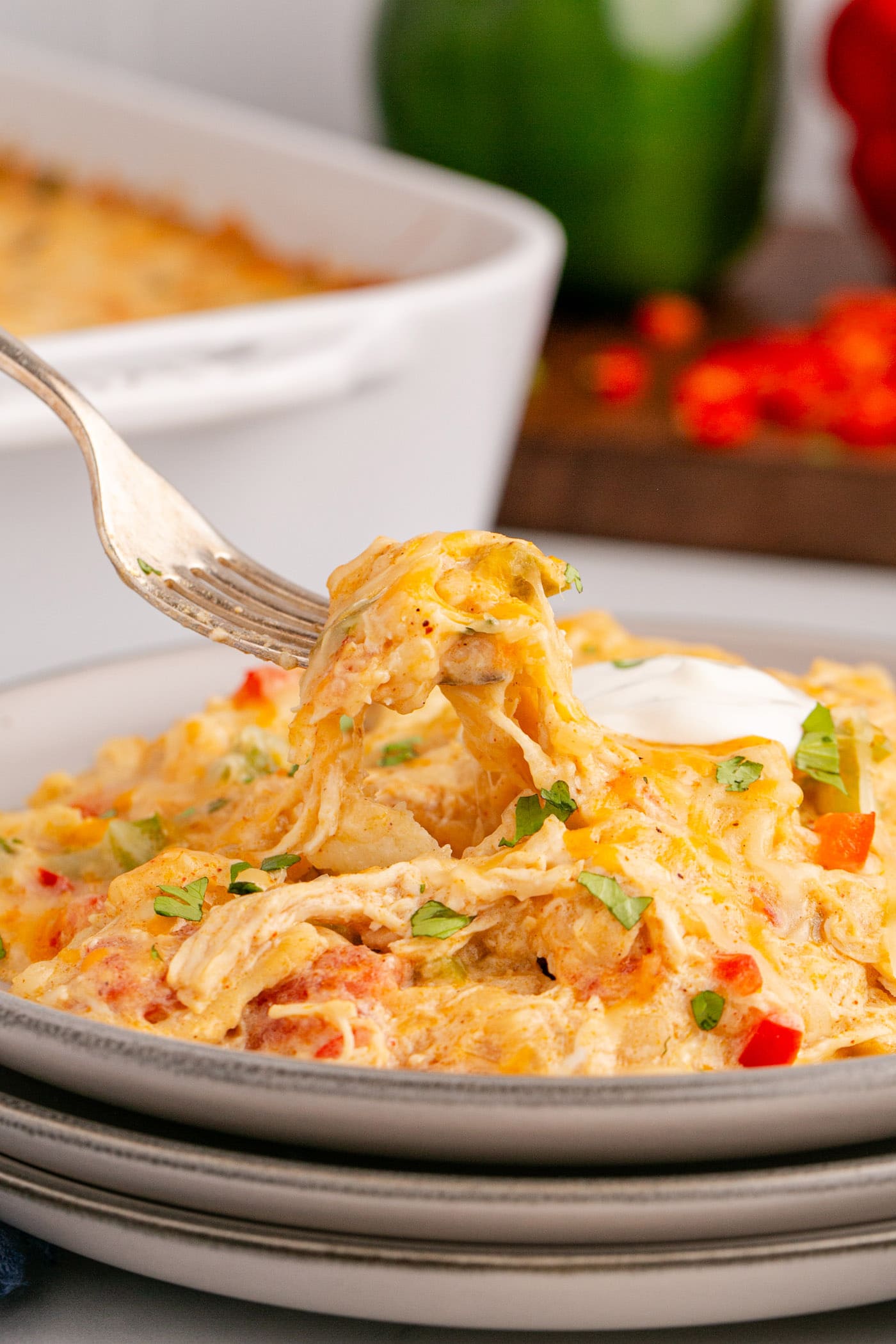 King Ranch Chicken Casserole on a fork held above a plate of King Ranch Chicken Casserole