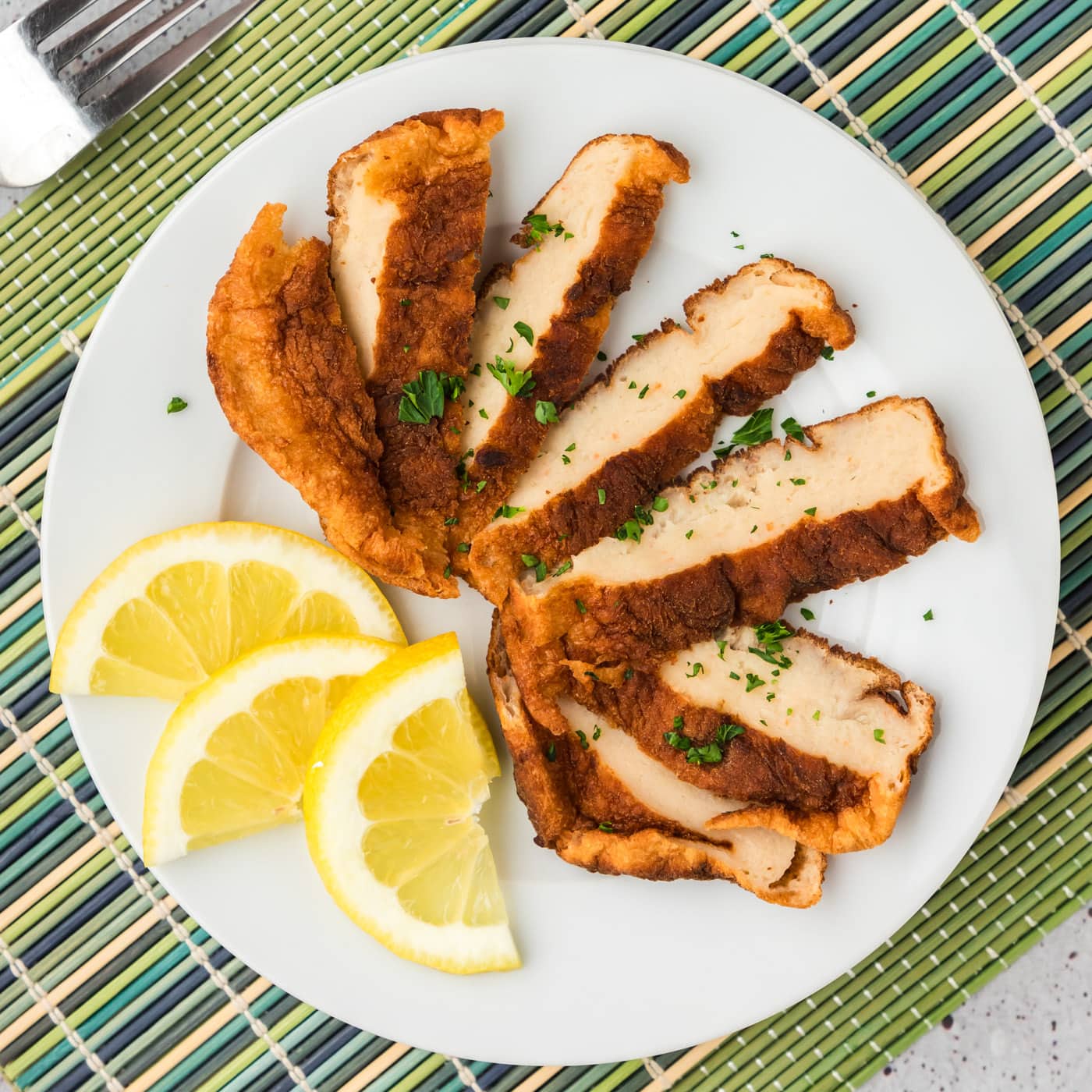 Overhead photo of a Korean Fish Cake sliced on a plate with lemon slices