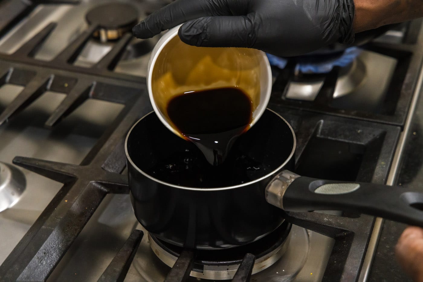pouring soy sauce into a saucepan