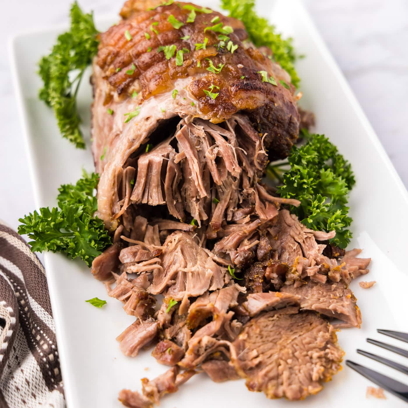 Close up photo of Leg of Lamb on a platter half shredded