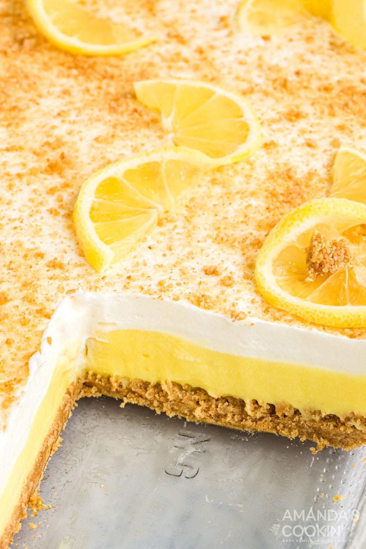 layered lemon dessert in a pan with a slice removed