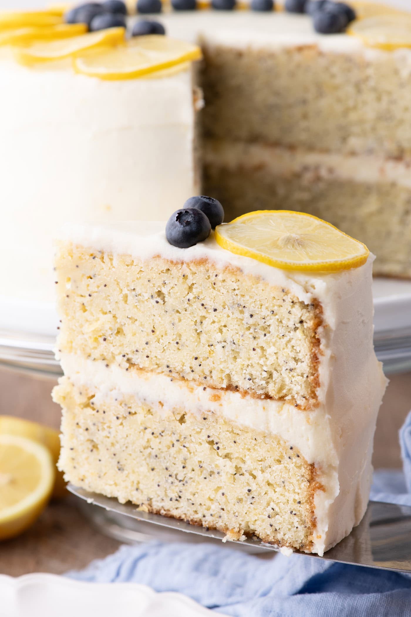 Slice of Lemon Poppy Seed Cake with the rest of the cake behind it