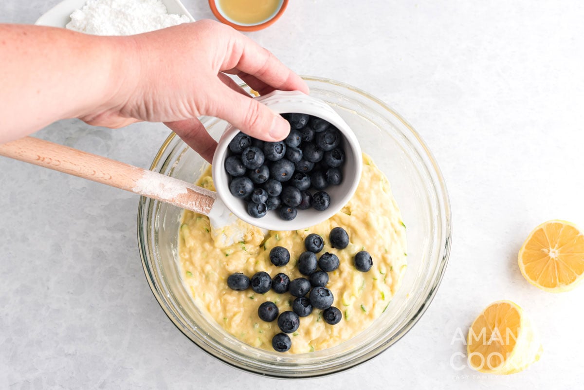 adding blueberries to bowl of batter
