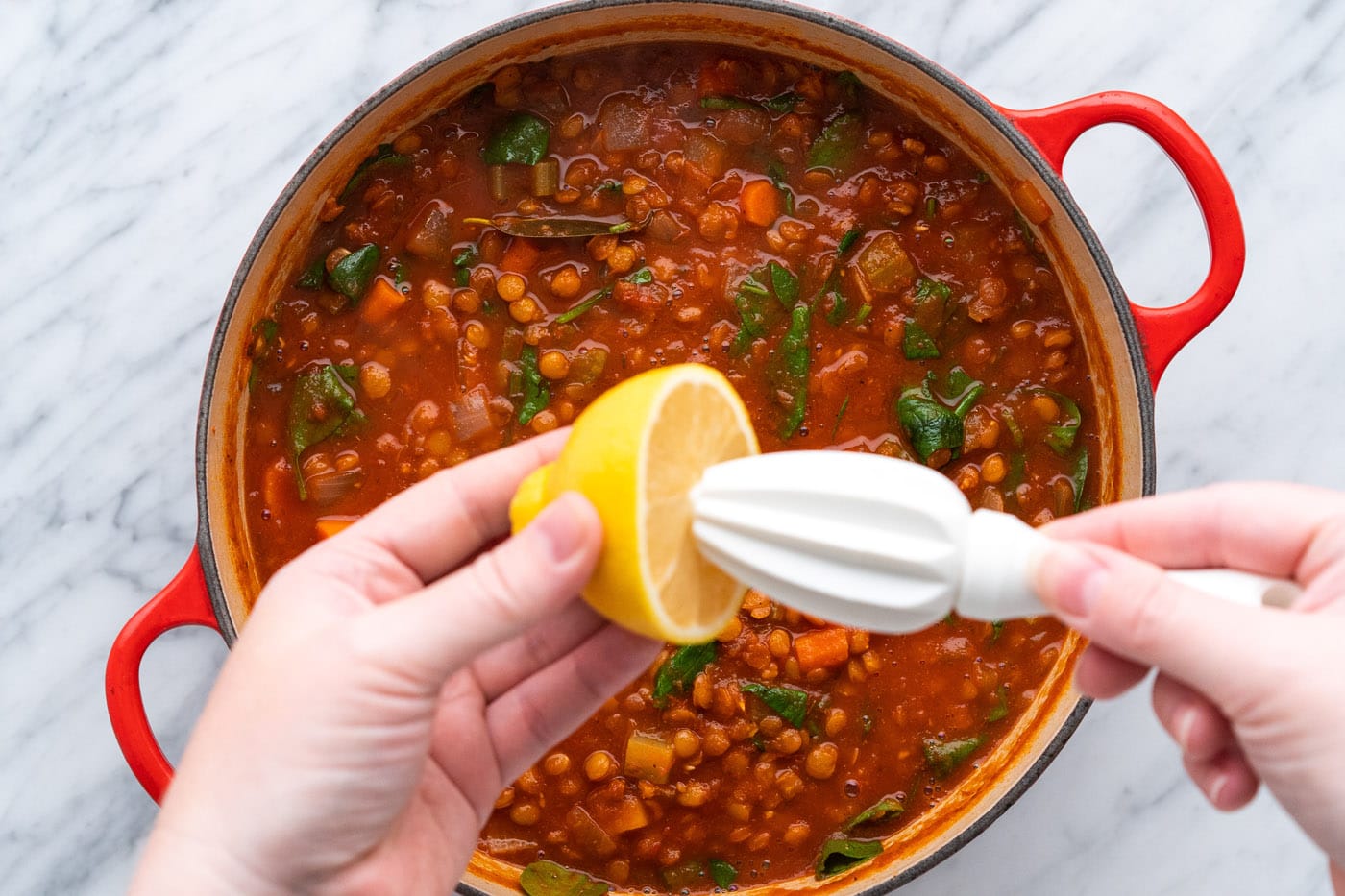 squeezing fresh lemon juice over lentil soup