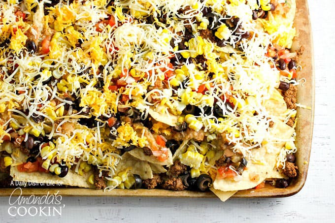 A close up overhead of loaded nachos on a baking sheet.
